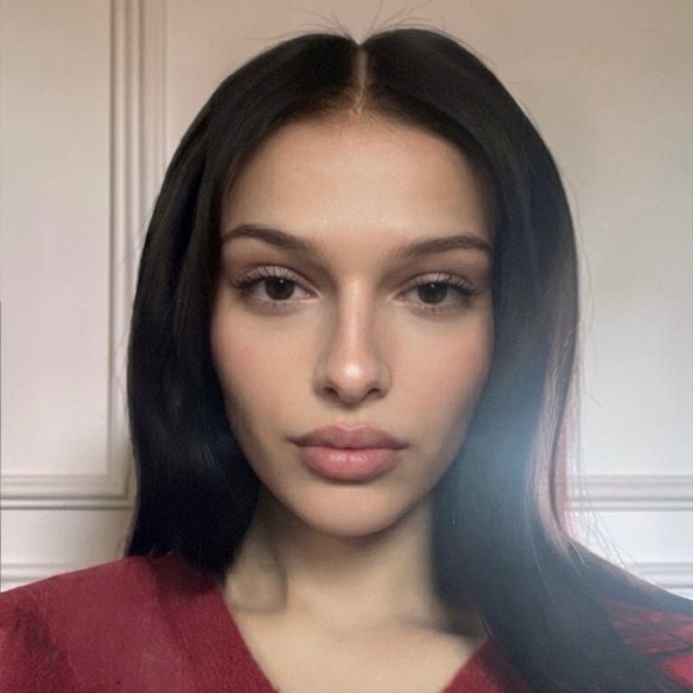 Portrait de face d'une cliente en haut rouge portant la perruque longue et lisse Naomi BYNERIMA.